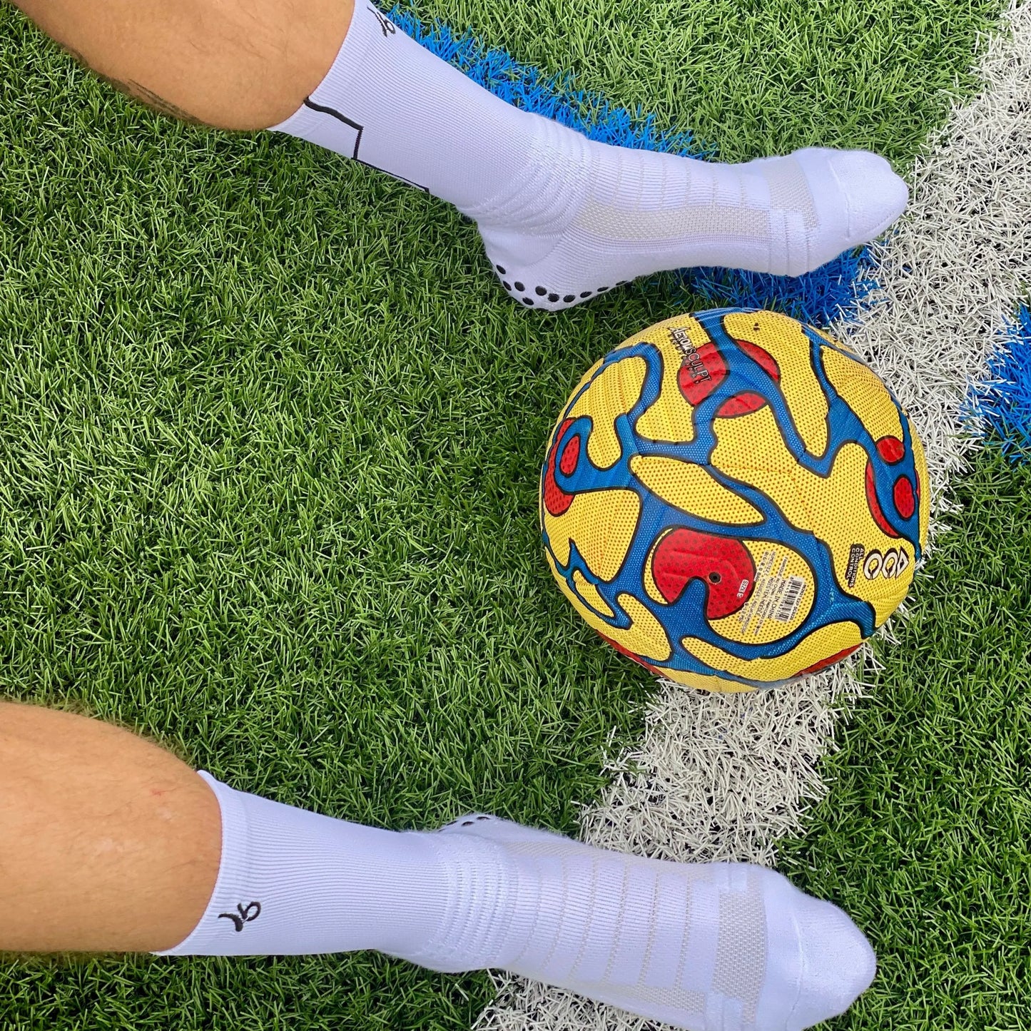 Athlète portant les chaussettes Joga sur le terrain avec un ballon de foot 