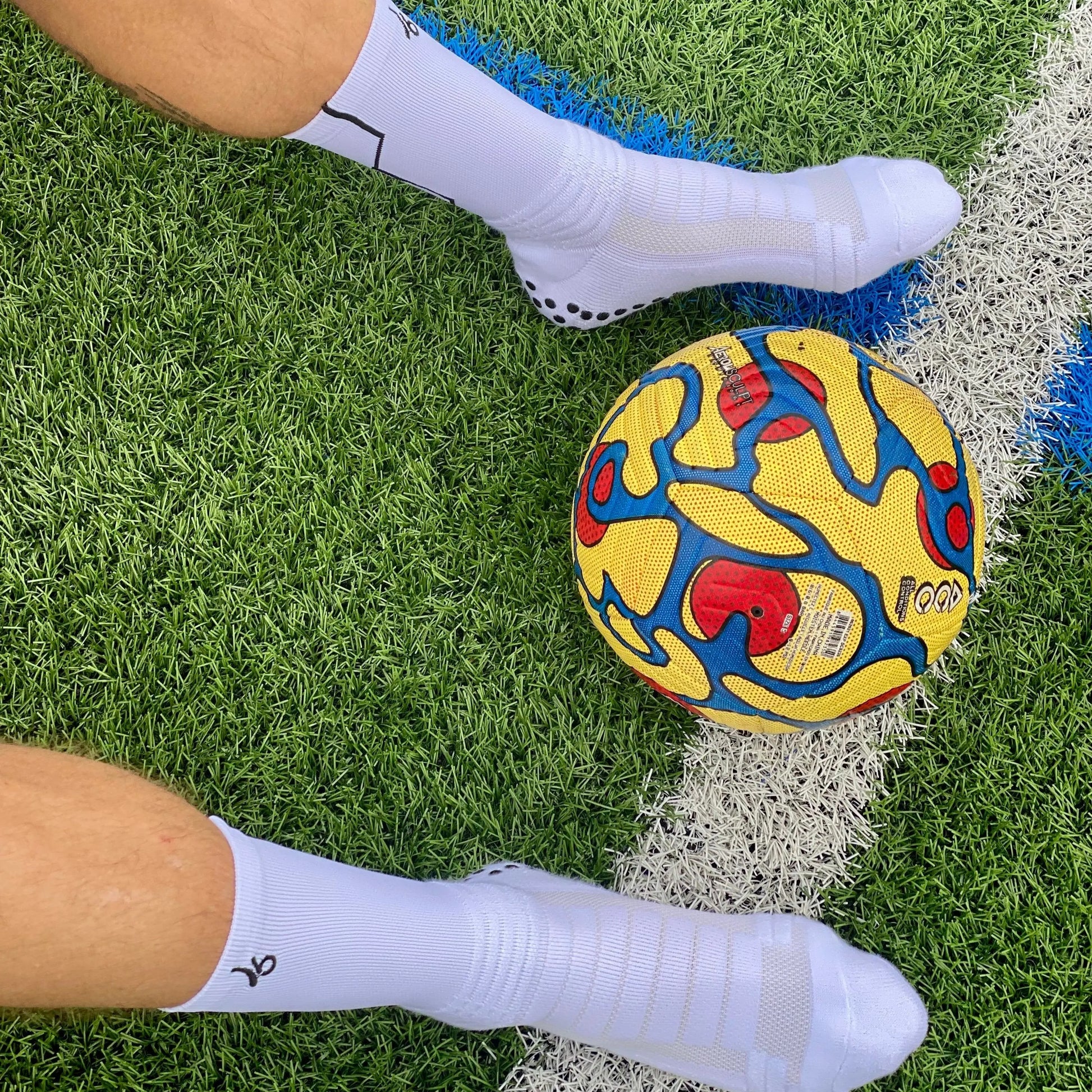 Athlète portant les chaussettes Joga sur le terrain avec un ballon de foot 