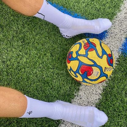 Athlète portant les chaussettes Joga sur le terrain avec un ballon de foot 